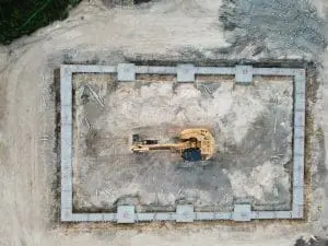An excavator performing groundwork on a foundation in southern maine