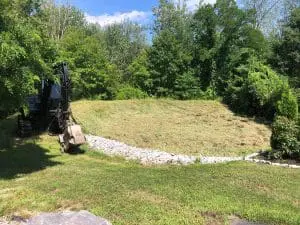 A tractor placing white rocks in a drain ditch