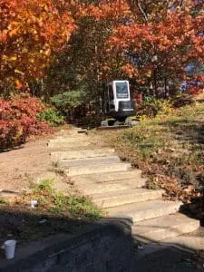an excavator doing site prep for an outdoor rock staircase installation