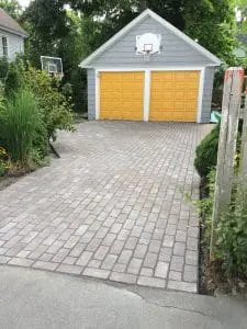 professionally hardscaped driveway leading up to a 2 car garage